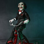 NECA ULTIMATE SAW BILLY THE PUPPET RIDING TRICYCLE WITH SOUND - 33 CM